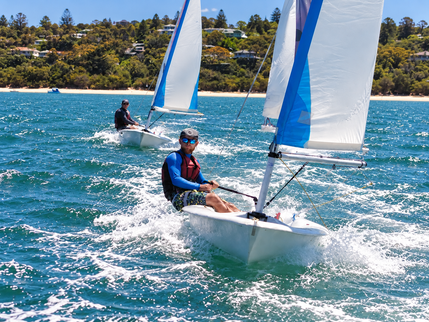 Two club members sailing a dinghy on a bright day